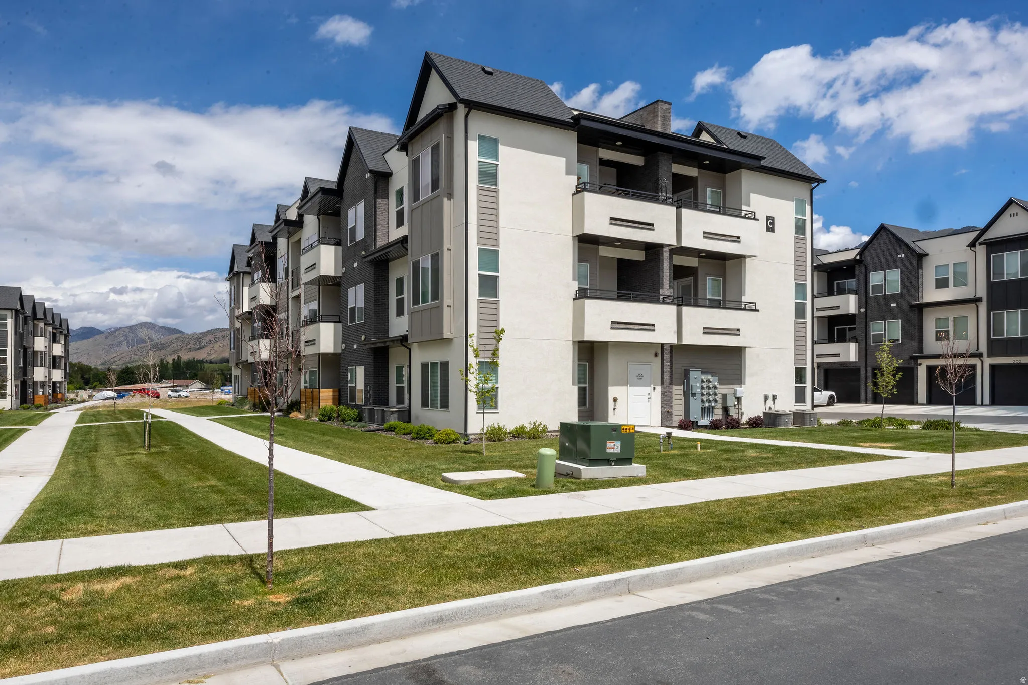 Contemporary multi-story building featuring light stucco and dark siding accents
