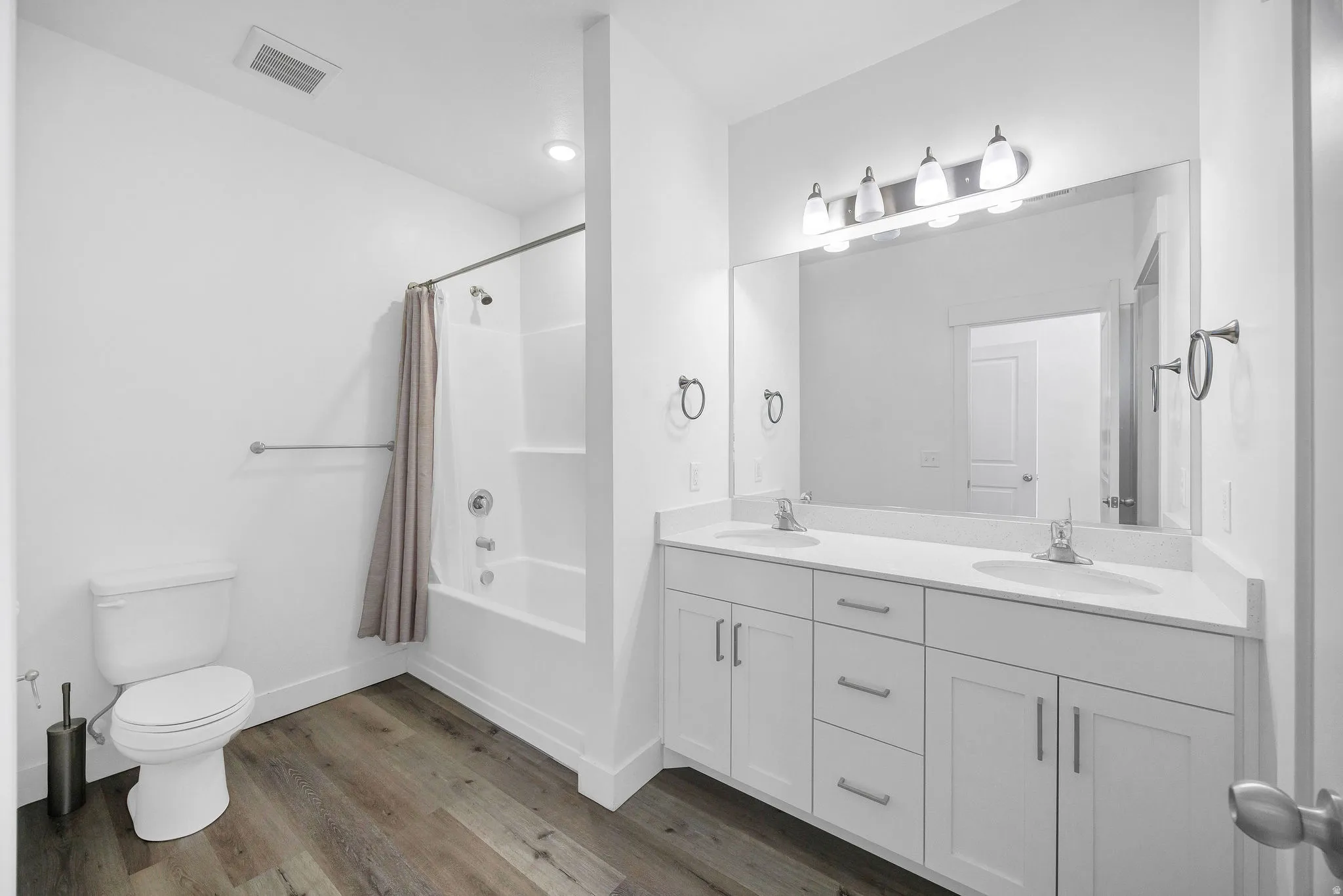 Bathroom featuring a dual vanity with white cabinetry, integrated sinks, and a large wall-mounted mirror