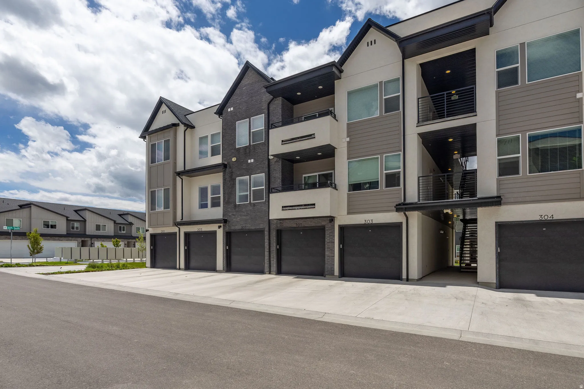 Contemporary multi-story exterior featuring a mix of light stucco, dark brick, and horizontal siding