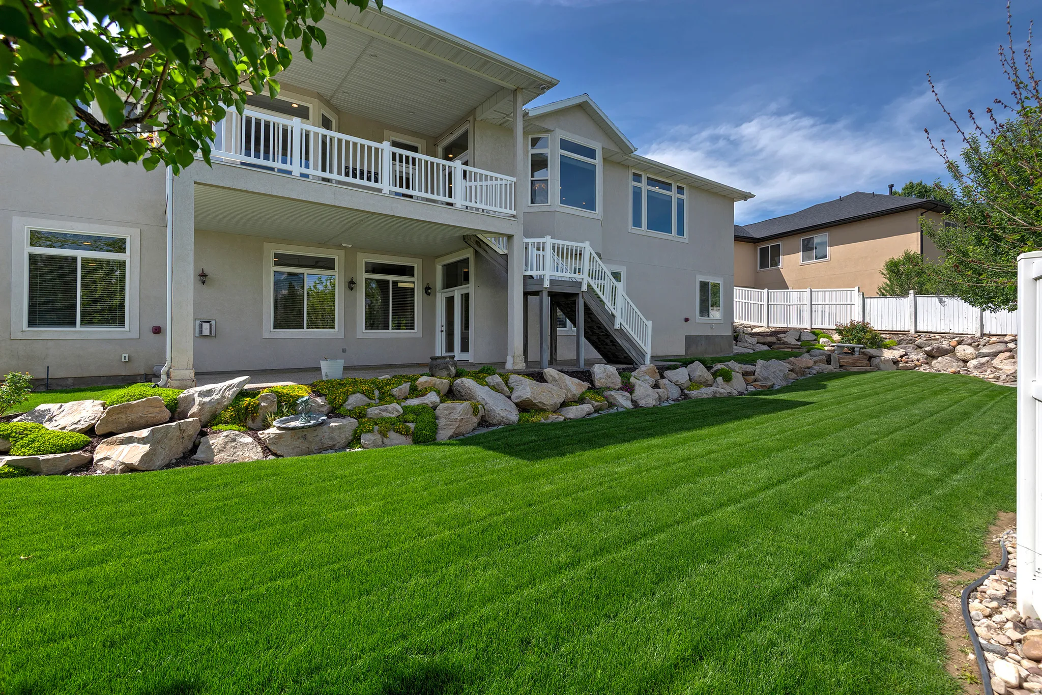 Expansive green lawn with a tiered rock garden featuring integrated plantings