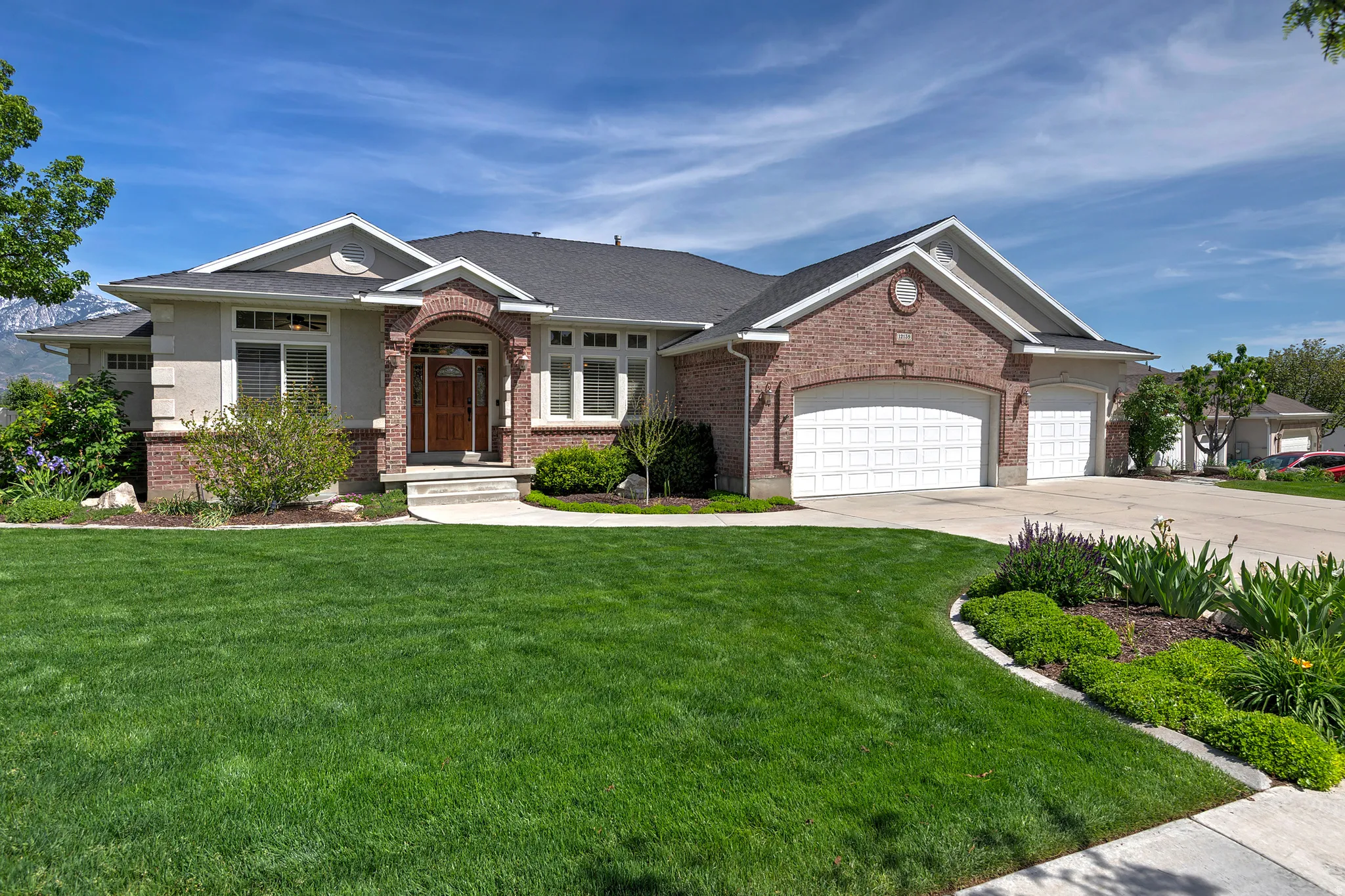 Brick and stucco exterior with multiple gables and a dark shingle roof