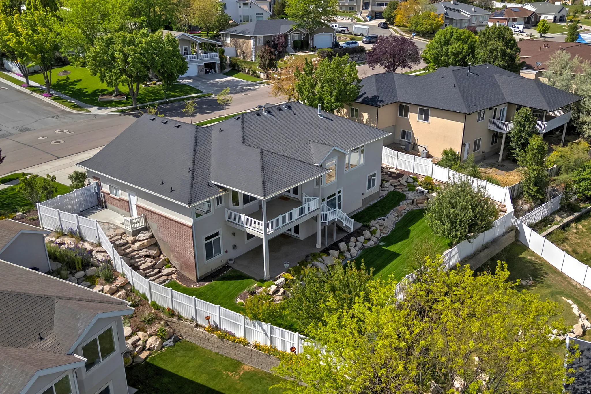 Multi-level property exterior with a dark shingle roof and light-toned siding