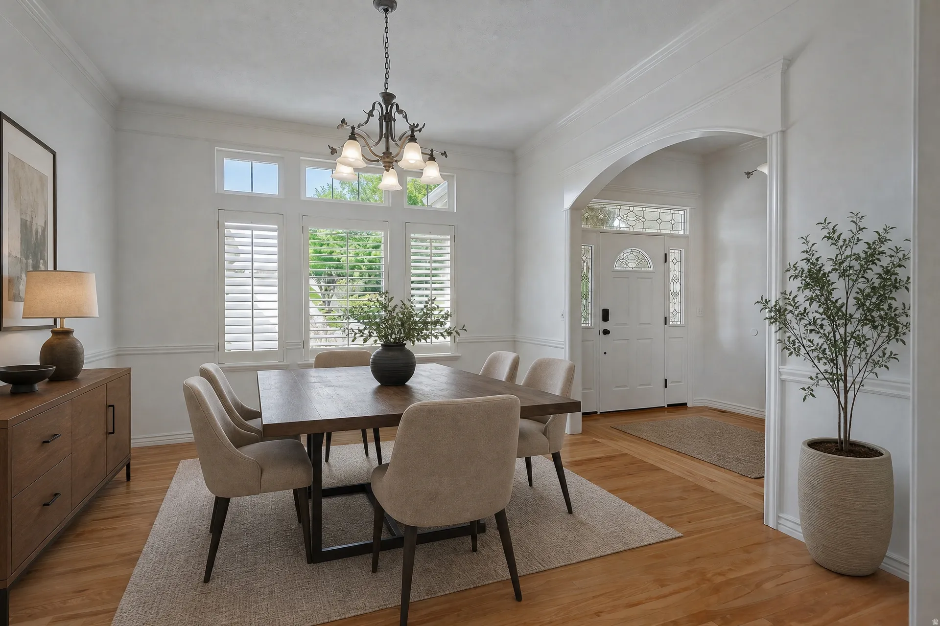 Bright dining area featuring hardwood flooring, an elegant chandelier, and wainscoting