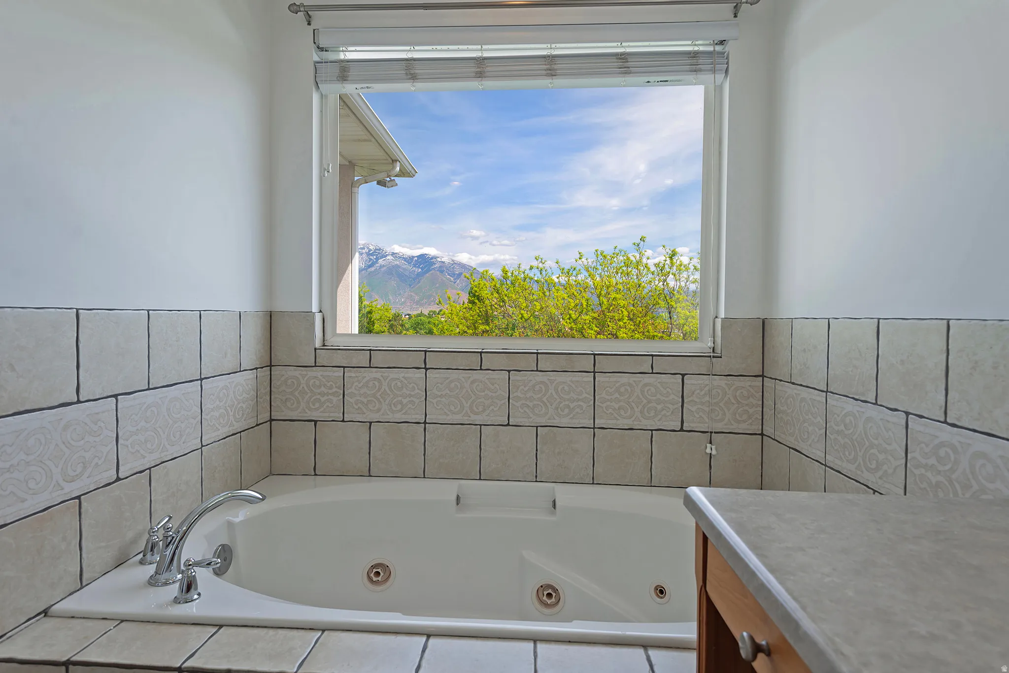 Soaking tub with a polished chrome faucet, surrounded by tiled walls and flooring