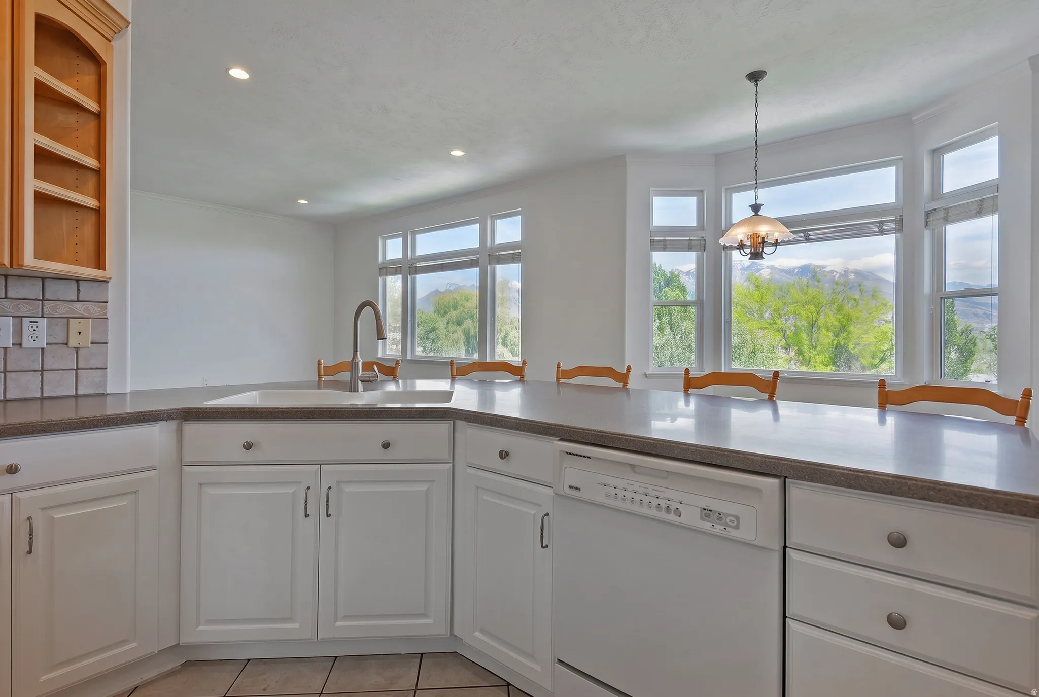 Kitchen featuring white cabinetry, a built-in dishwasher, and an integrated sink with a gooseneck faucet