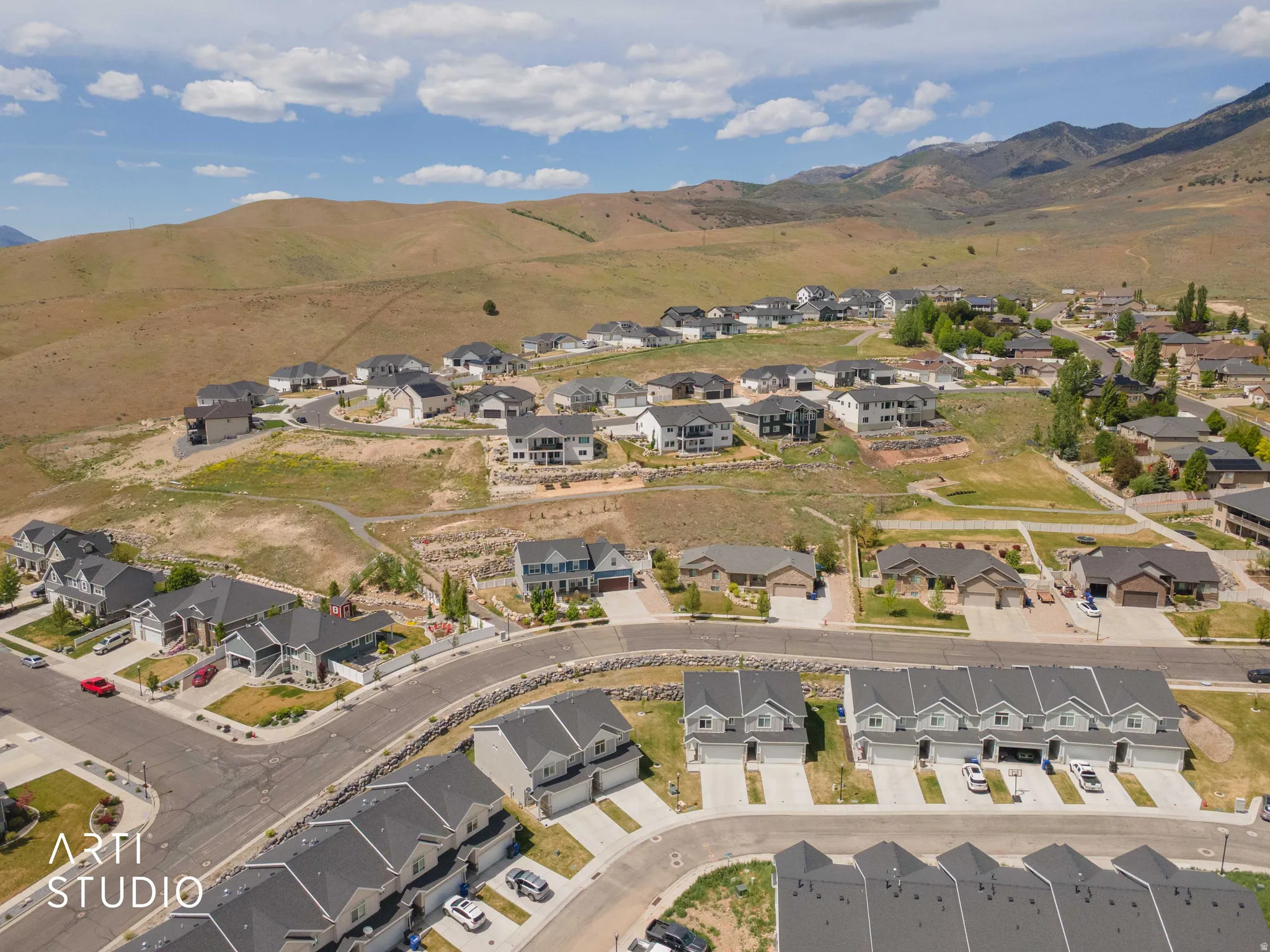 Expansive residential community featuring a mix of single-family homes and townhomes, set against a backdrop of natural hills and distant mountains