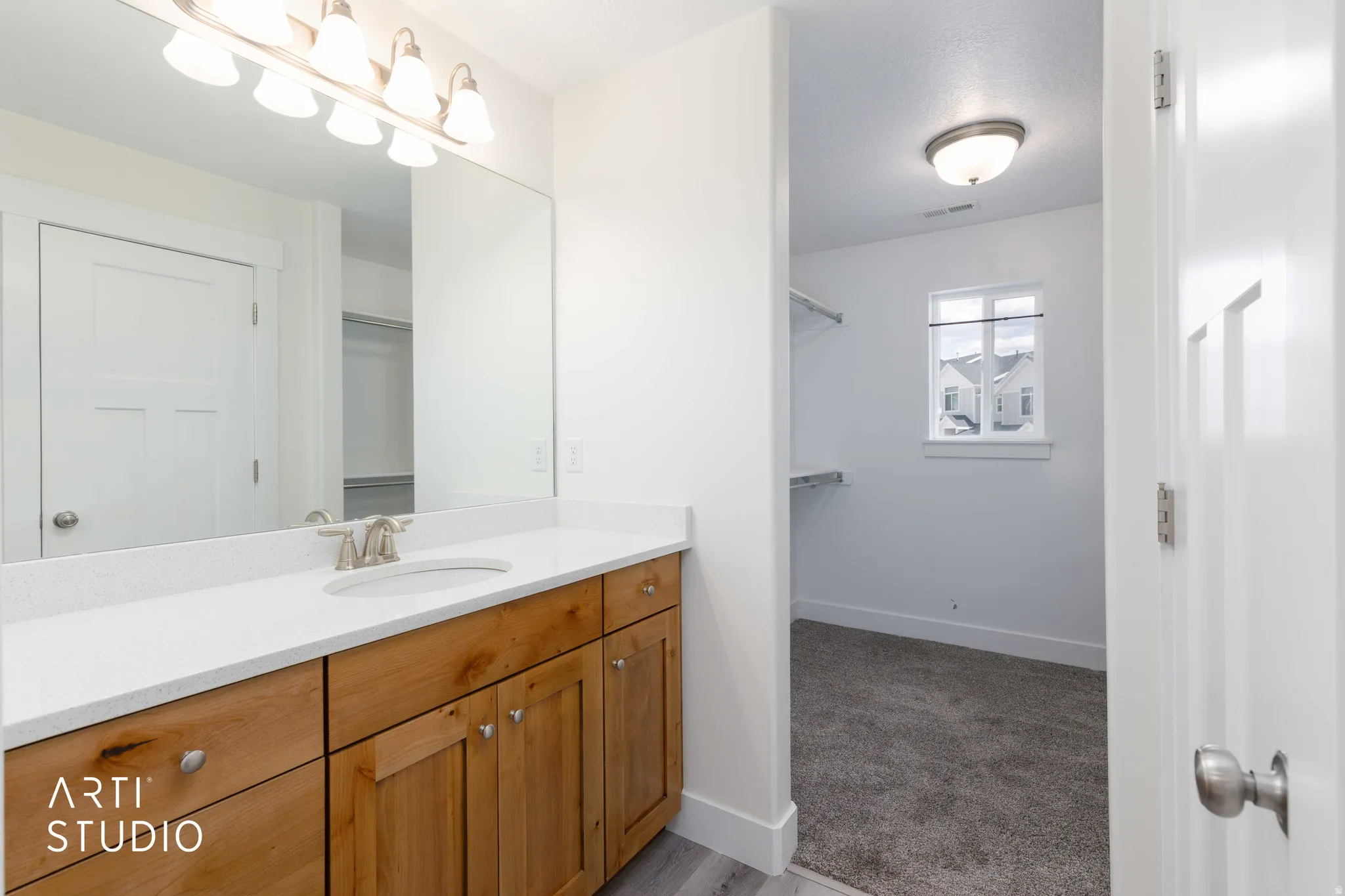 Bathroom vanity featuring a light wood-finish cabinet, white countertop, and brushed nickel faucet