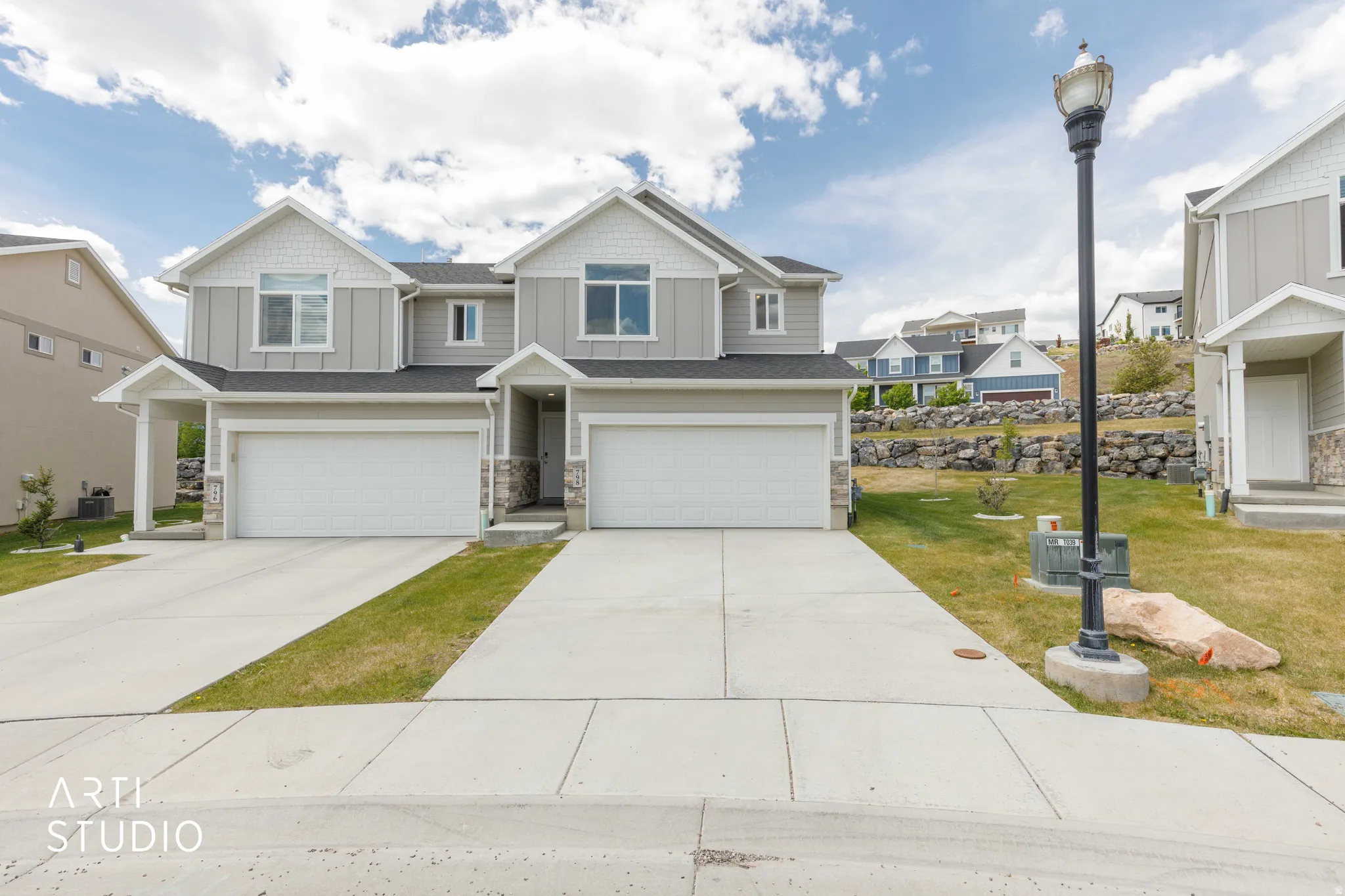 Modern duplex exterior featuring light gray siding with white trim accents and dark roofing