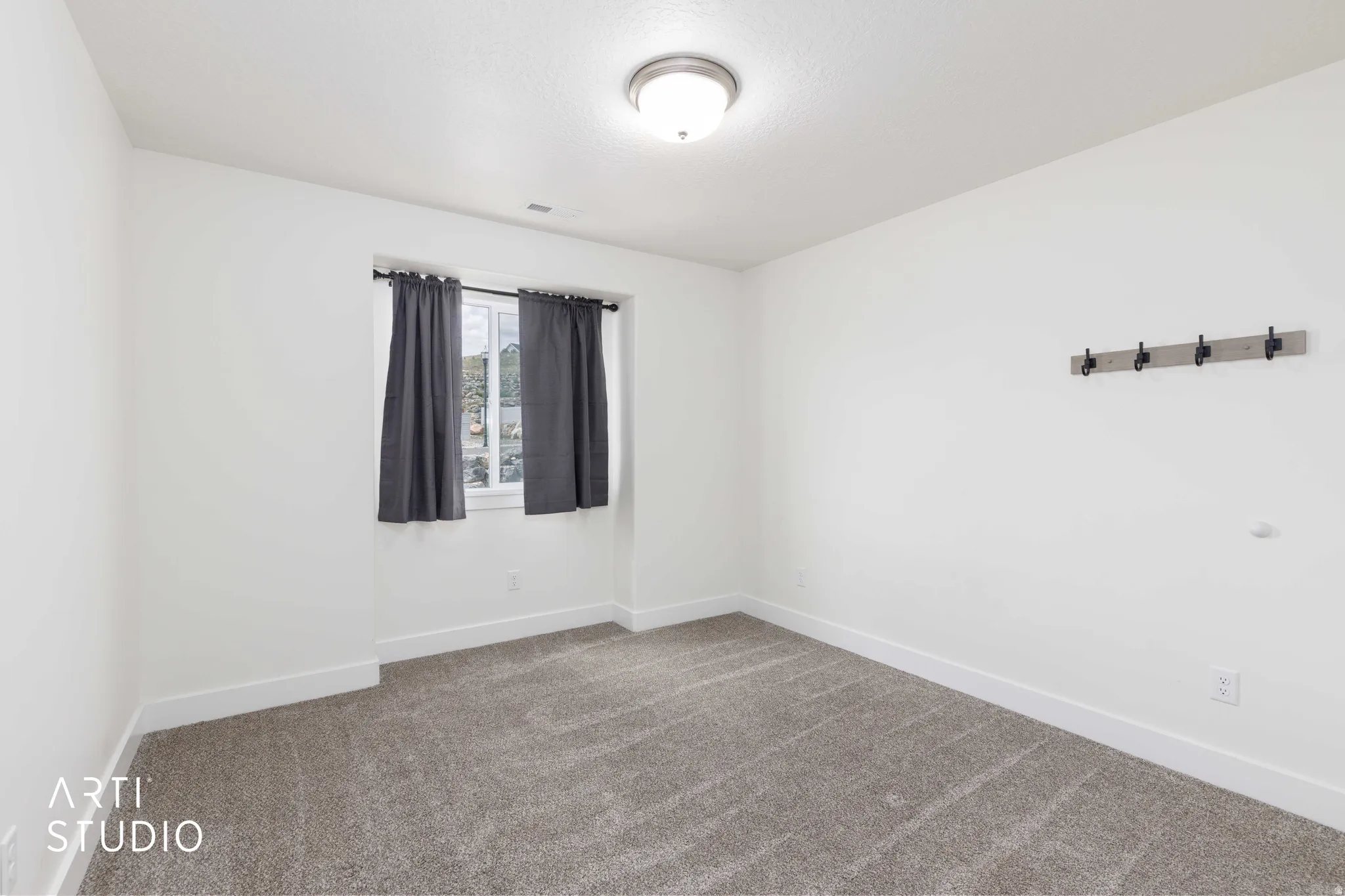 Neutral interior space featuring light-toned walls, textured carpeting, and a flush-mount ceiling light