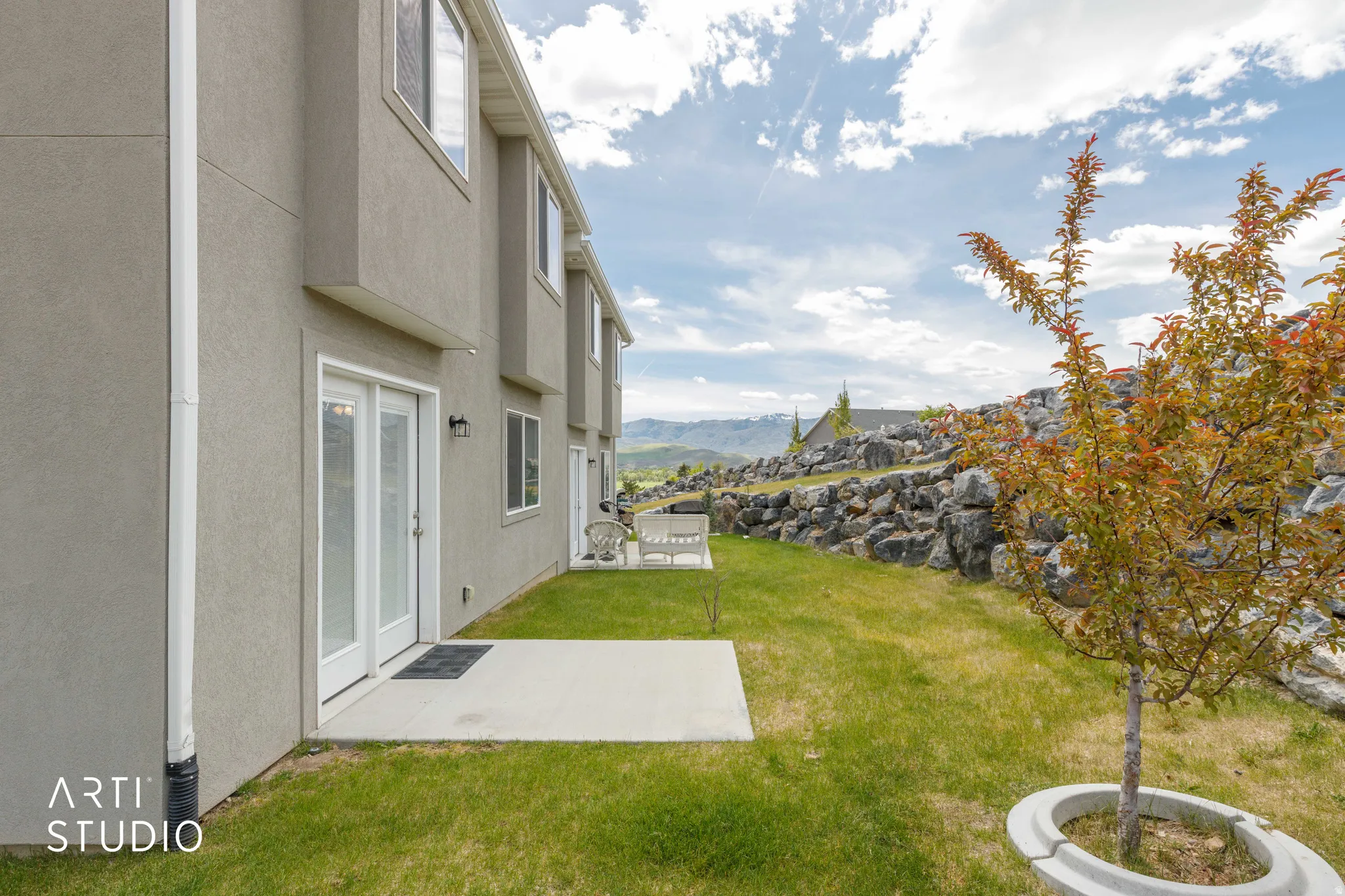 Rear exterior featuring a concrete patio, stucco siding, and double glass doors