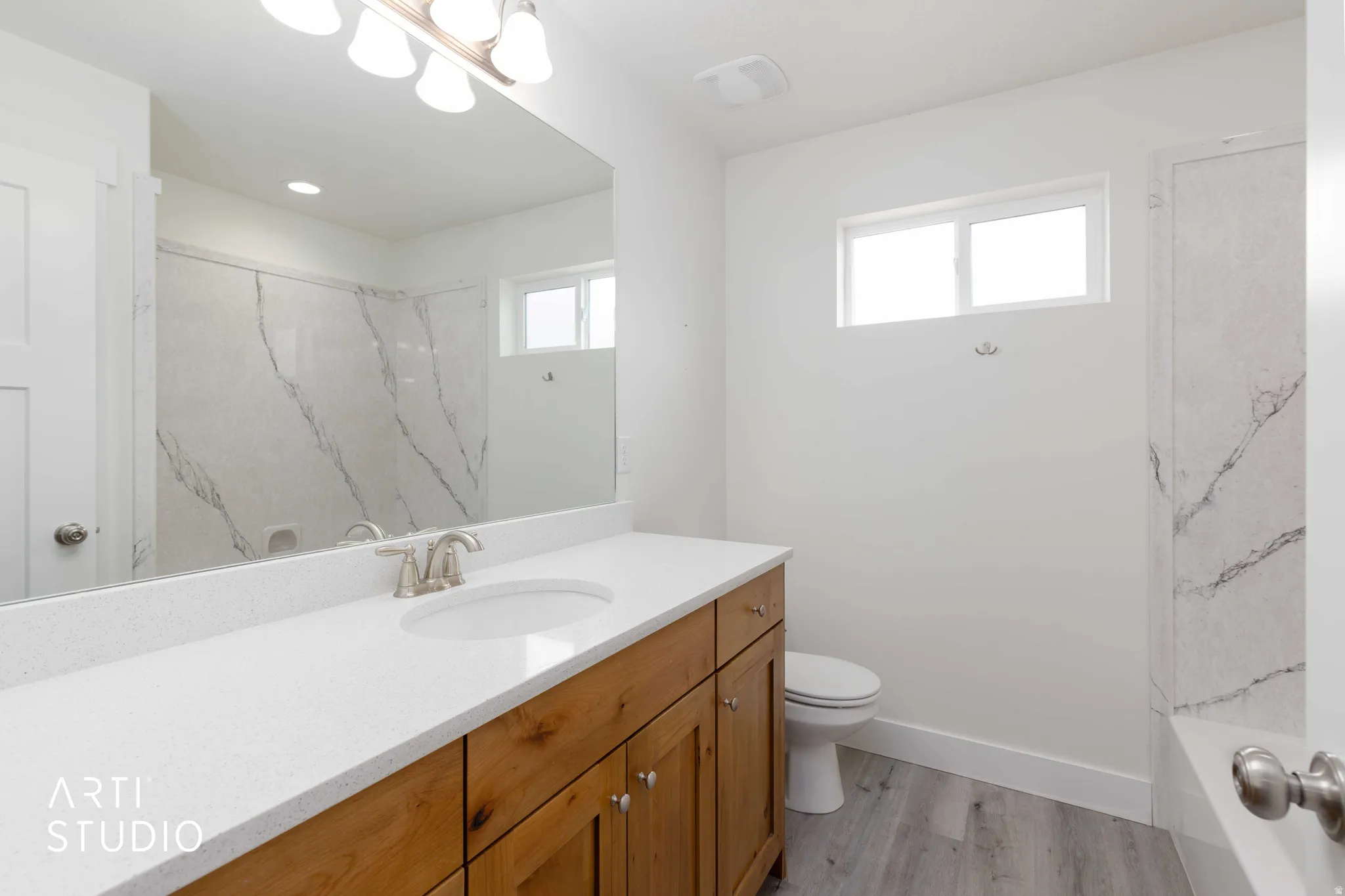 Bathroom featuring a wood-finish vanity with a white countertop, an undermount sink, and a large mirror