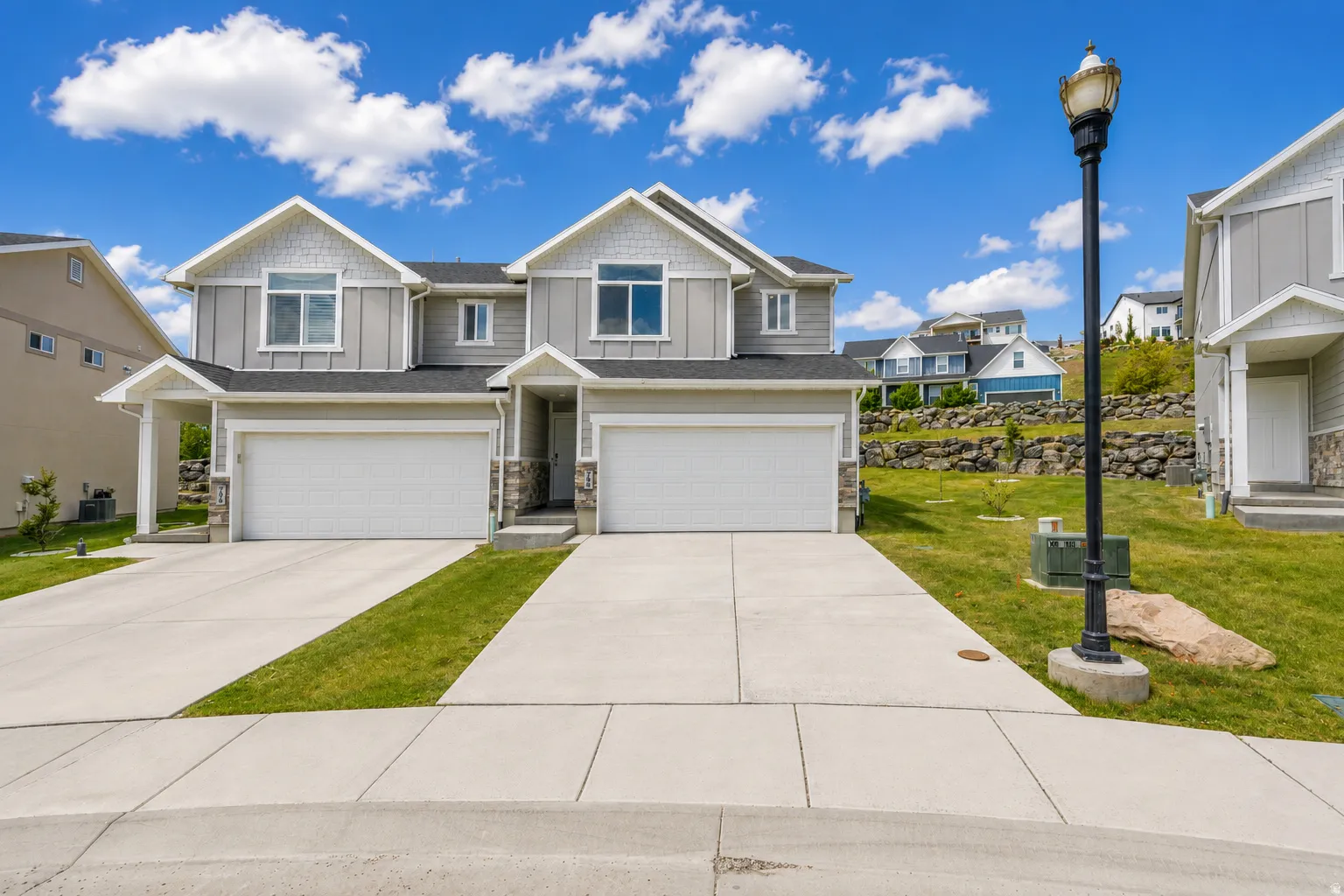 Two-story residence featuring light gray siding, white trim, and stone accents