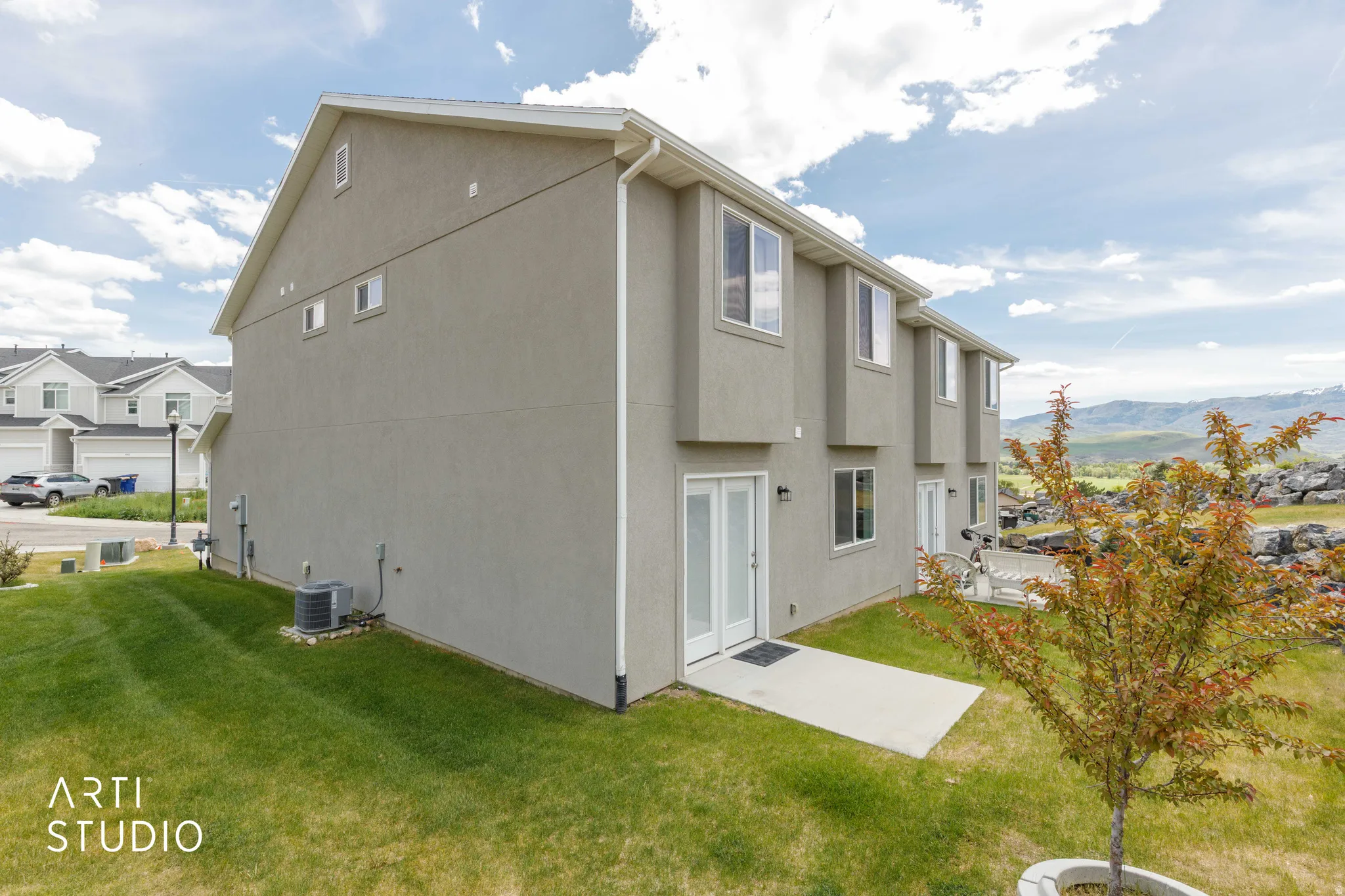 Stucco exterior featuring multiple windows and two sets of double doors opening to a concrete patio