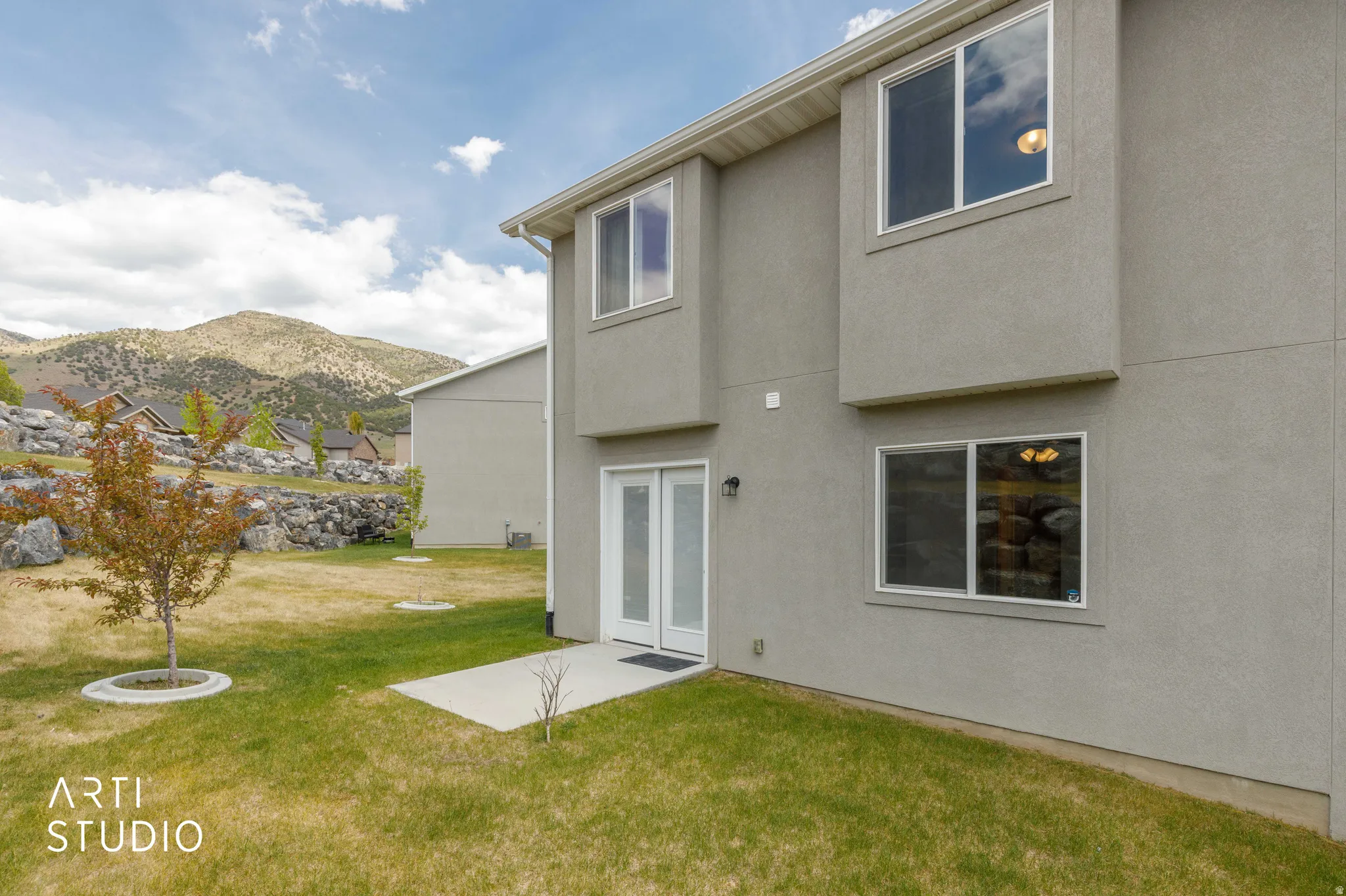Stucco exterior featuring multiple windows and a double glass door