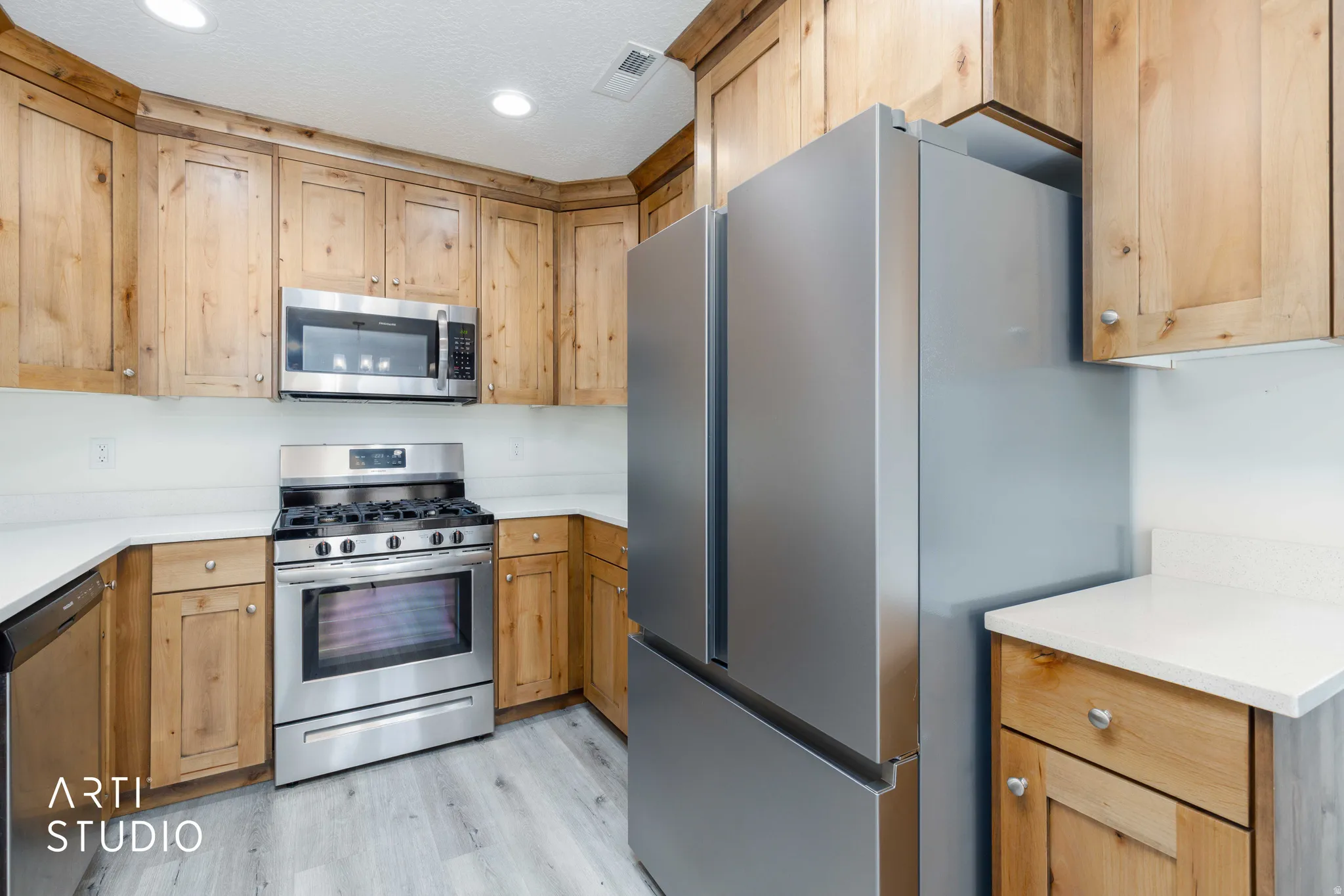 Kitchen featuring light wood-finish cabinetry, stainless steel appliances, a gas range with an oven, and light-toned countertops