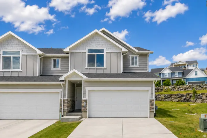 Contemporary exterior featuring light gray siding, white trim, a covered entry, and attached garages