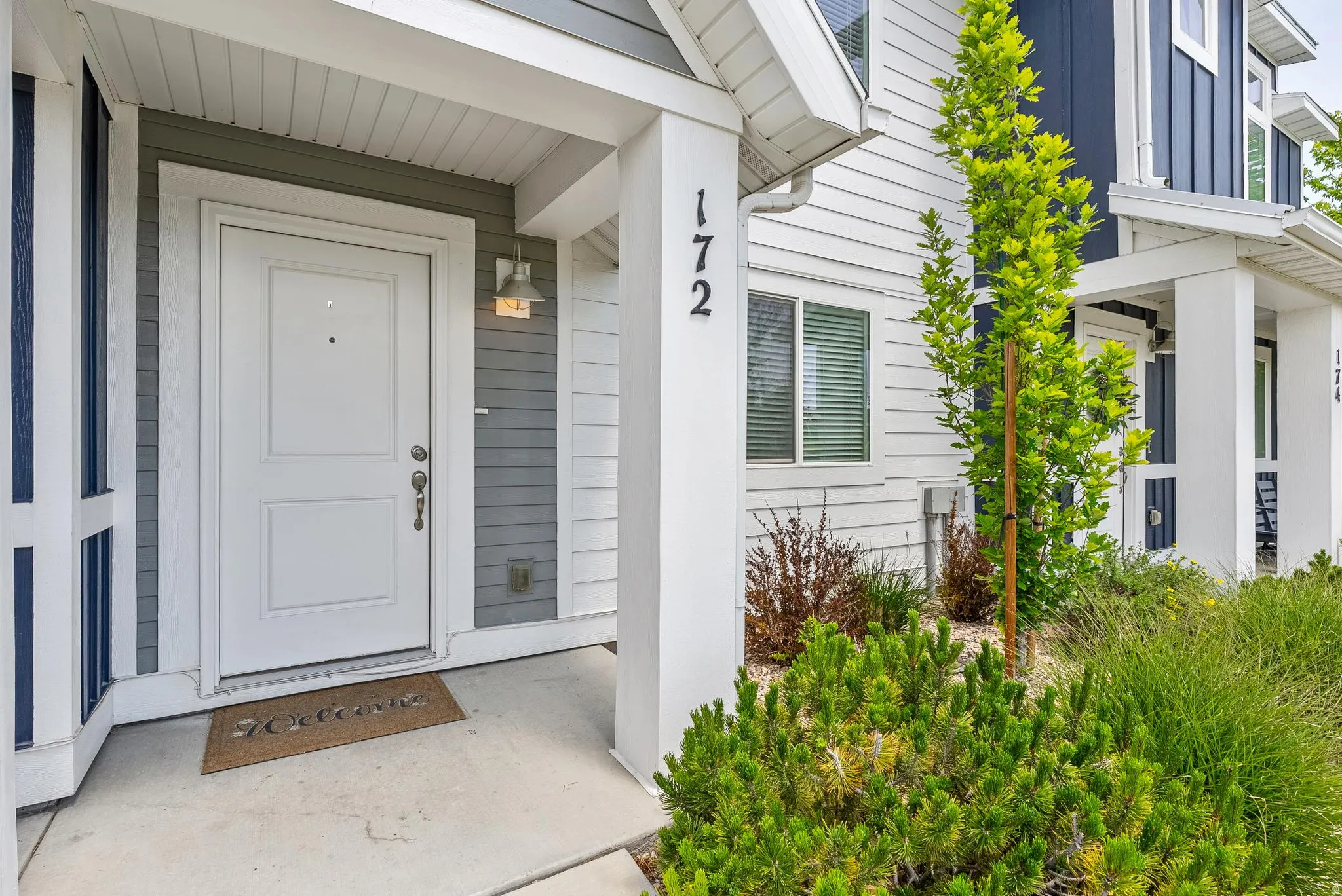 Entryway featuring a white paneled door, gray horizontal siding, and a wall-mounted exterior light fixture