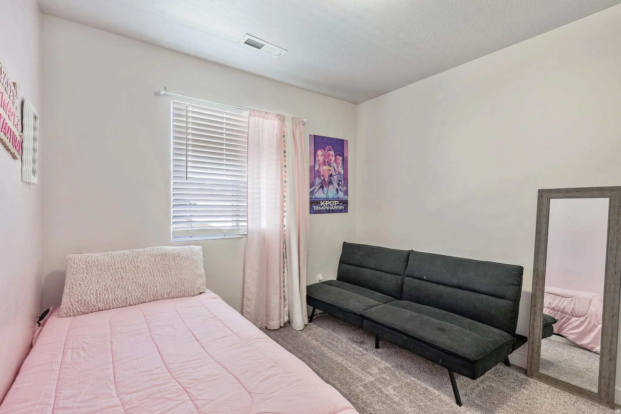 Carpeted room featuring a single window with blinds and sheer curtains, complemented by light-colored walls and a ceiling vent
