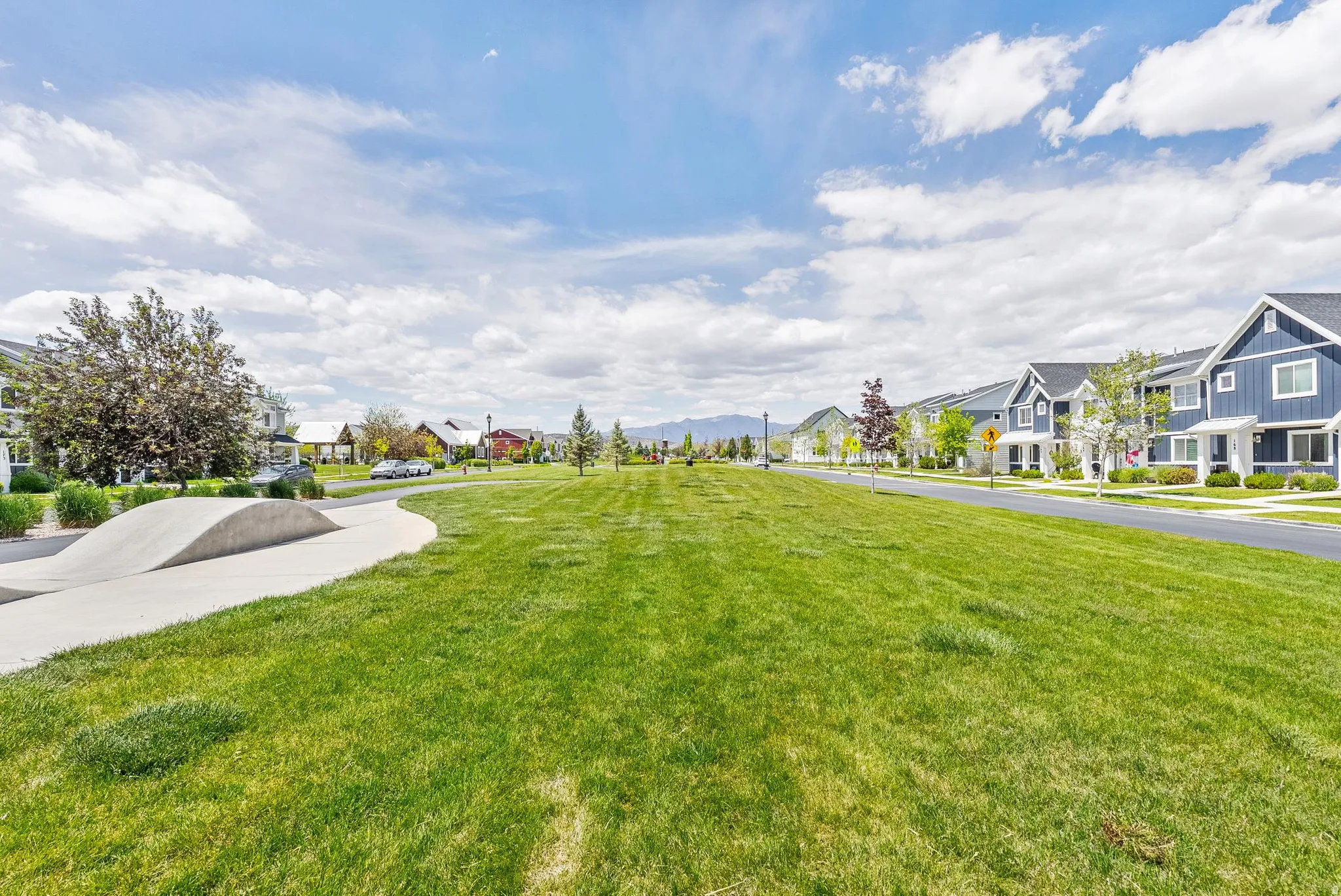 Expansive green space featuring a concrete skate park element and paved pathway