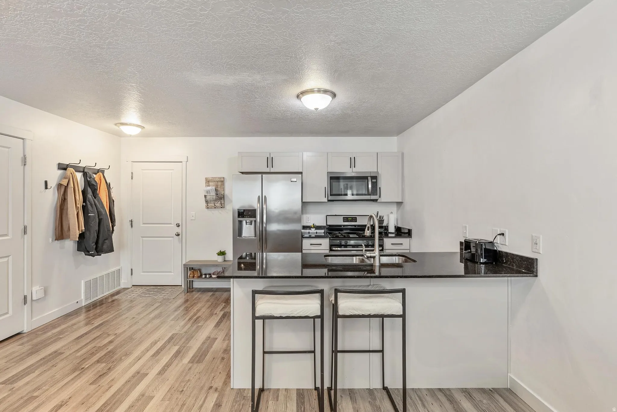 Kitchen featuring stainless steel appliances, light-toned cabinetry, and dark countertops with a breakfast bar