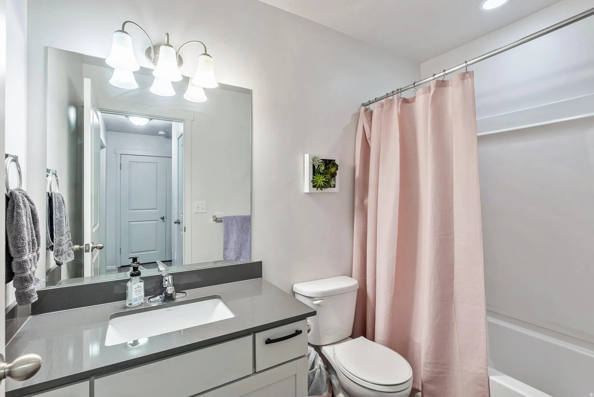 Full bathroom featuring a rectangular integrated sink, gray countertop, and white cabinetry with matte black hardware