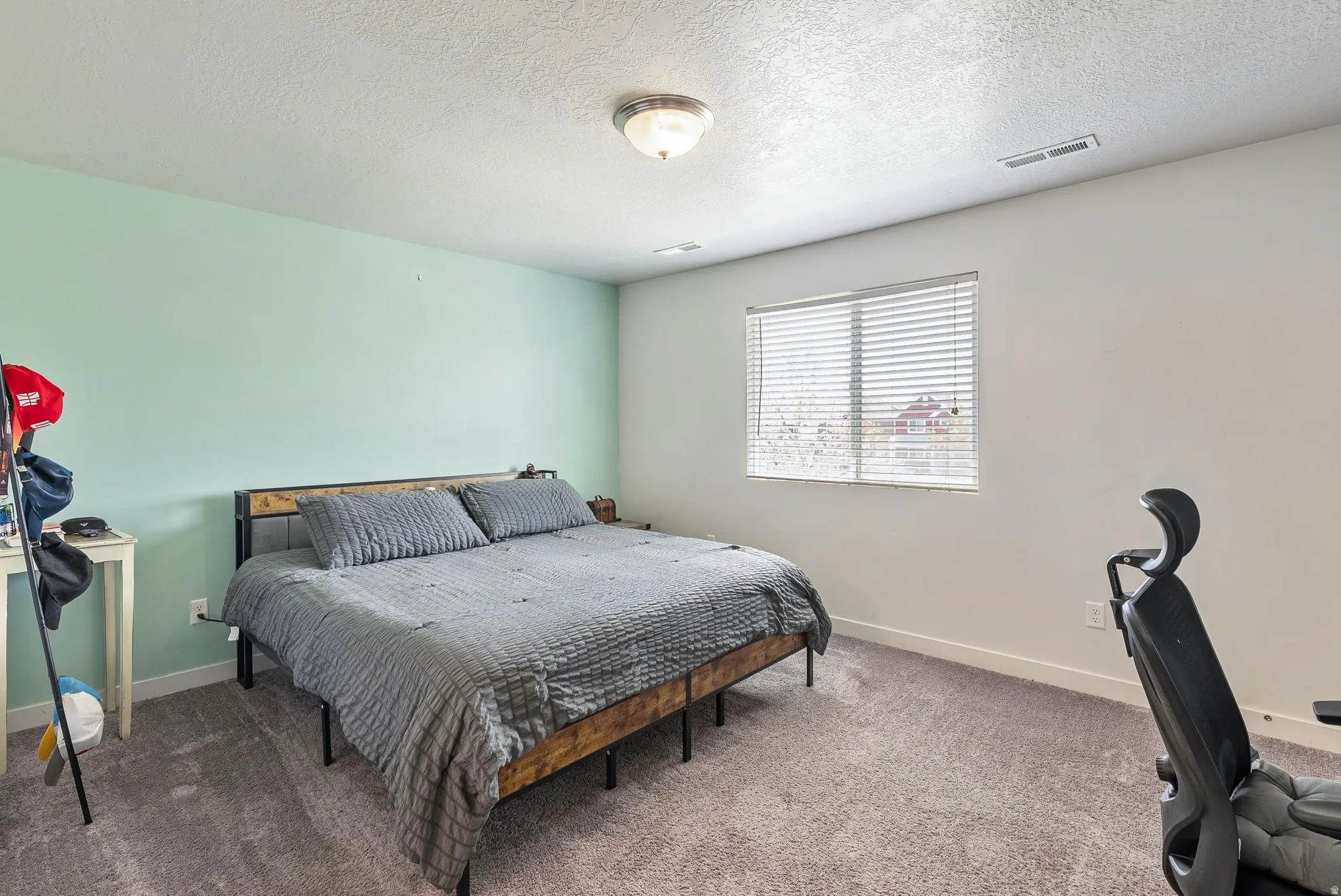 Carpeted room featuring a window with blinds, ceiling light fixture, and light-colored walls