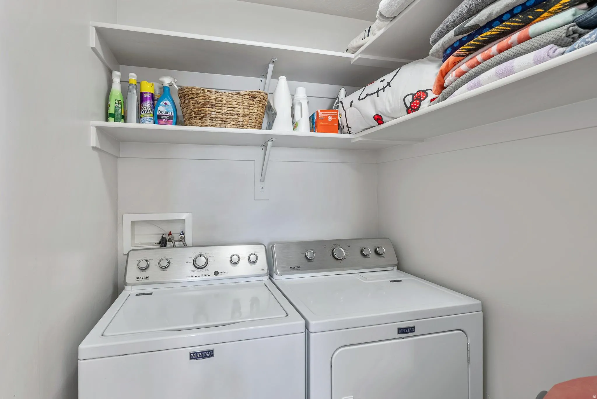 Dedicated laundry area featuring a washer and dryer, integrated wall shelving, and utility hookups