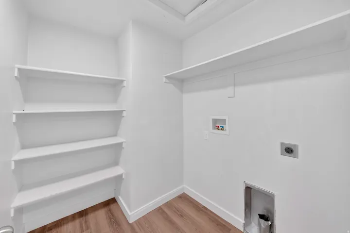 Utility room featuring a long upper shelf, four corner shelves, wood-finish flooring, and white baseboards