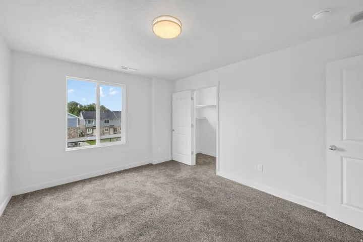 Bright room featuring white walls, gray textured carpet, and a large window