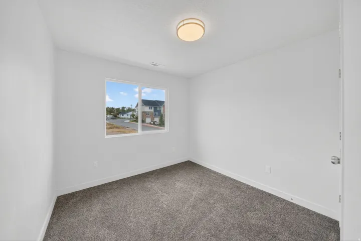 Bright room featuring a double-pane window, neutral-toned walls, gray carpeting, and a flush mount ceiling light