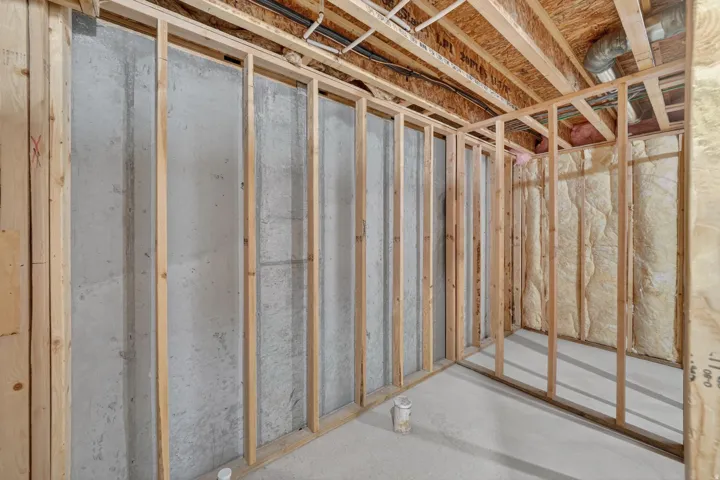Unfinished basement space featuring concrete walls, wood framing, and exposed ceiling joists