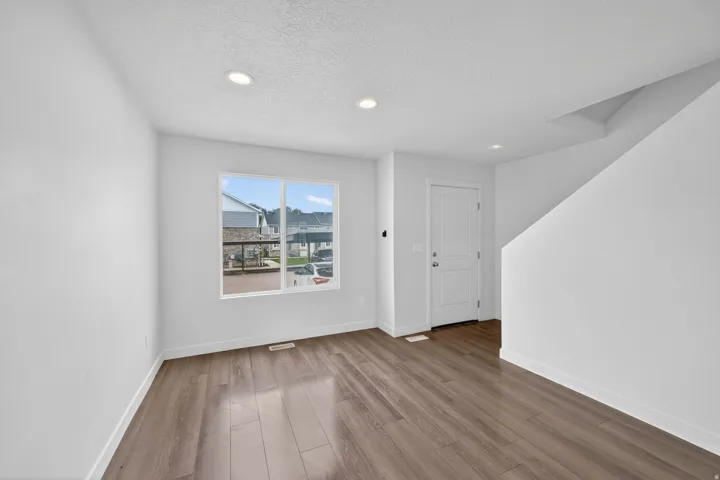 Bright interior space featuring wood-finish flooring, recessed lighting, and a white entry door