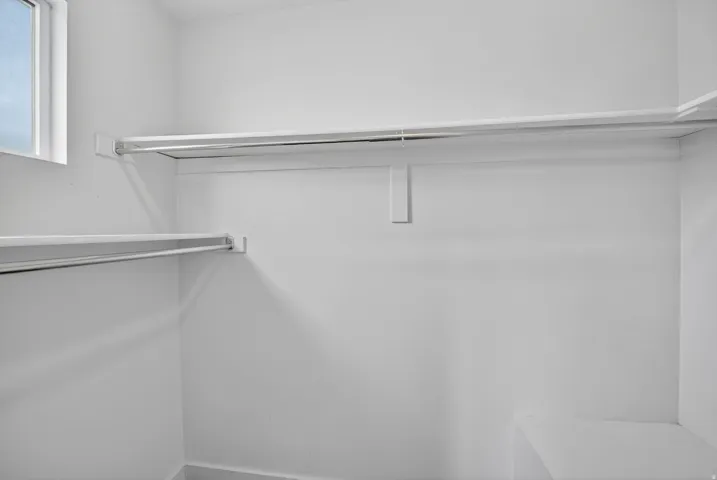 Walk-in closet featuring white wire shelving, hanging rods, and a built-in corner shelf