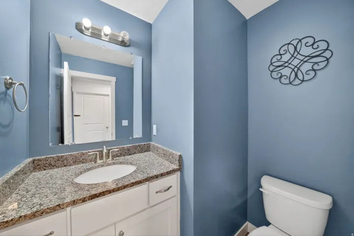 Bathroom featuring a white vanity with brushed nickel hardware, a speckled stone countertop, and an undermount sink