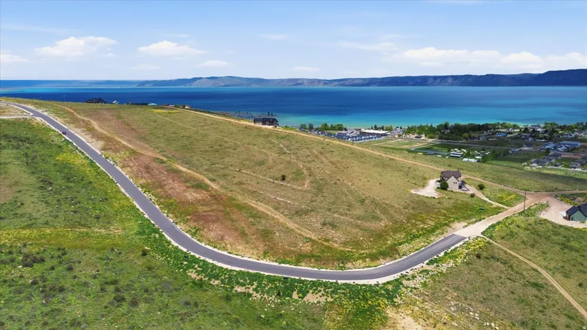 Expansive undeveloped land featuring a paved road, undulating terrain, and distant water frontage
