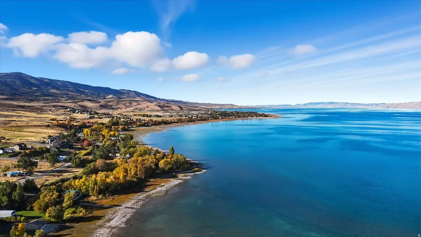 Expansive waterfront property featuring a substantial body of water, a treeline with autumn foliage, and distant mountains