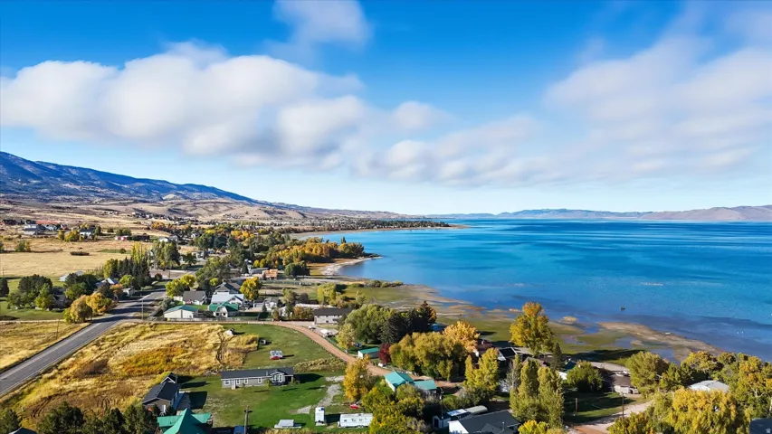 Expansive lakefront setting featuring a broad body of water, a shoreline with foliage, and a surrounding landscape of hills