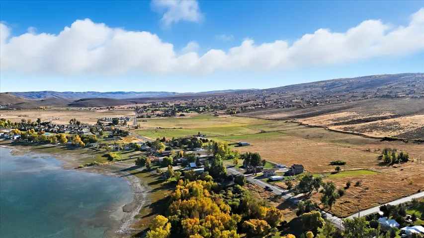 Expansive landscape featuring a large body of water, rolling hills, and scattered residential properties