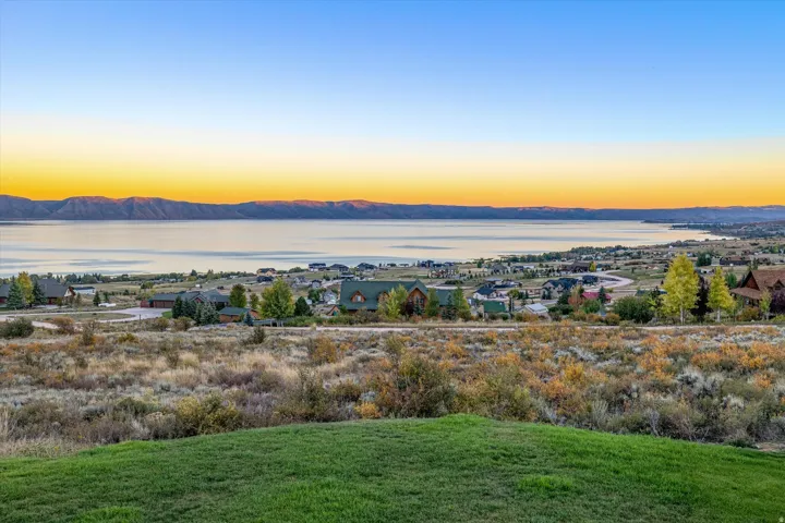 Expansive outdoor space featuring a manicured lawn, natural scrub brush, and distant homes
