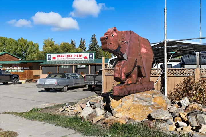 Paved parking area featuring a prominent bear sculpture on a stone base