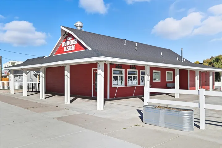 Commercial building featuring vibrant red siding and a dark shingle roof