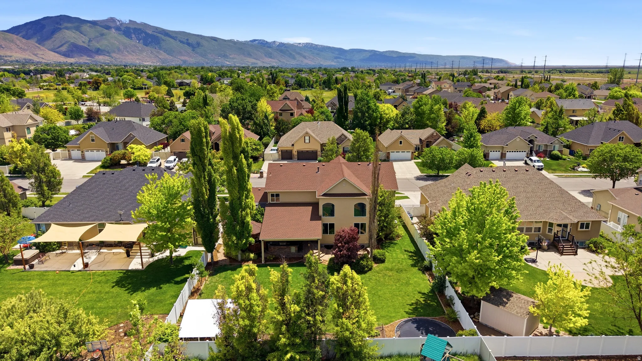 Expansive residential property featuring a large green lawn, mature trees, and a mountain backdrop