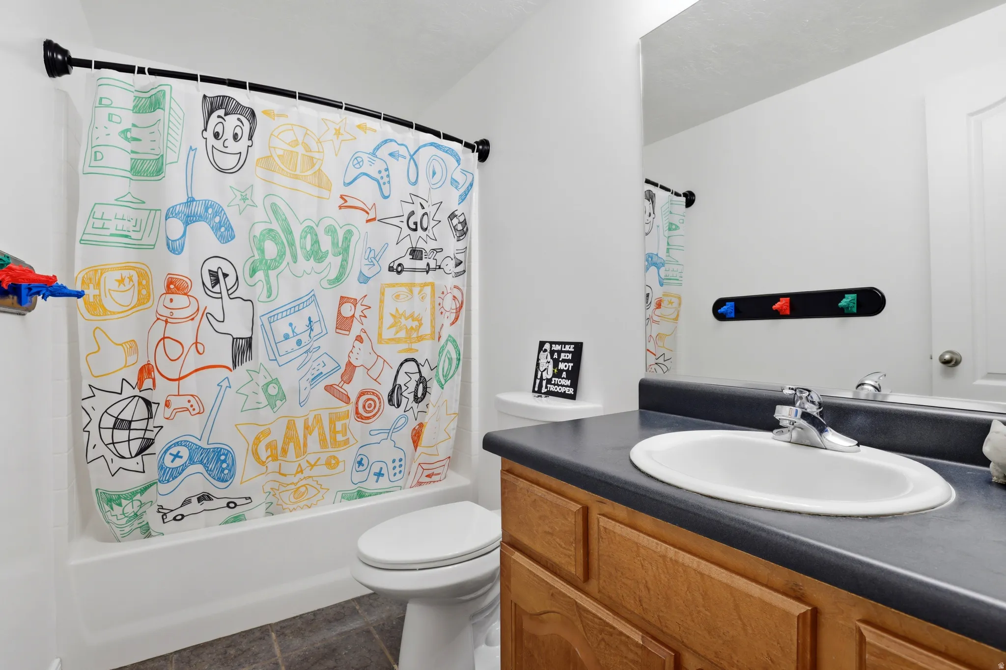 Bathroom featuring a built-in wood-finish vanity with a dark countertop and integrated sink, a large wall mirror, and a toilet