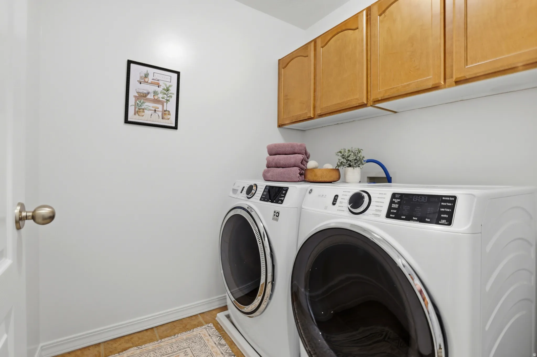Laundry area featuring upper cabinetry, light-toned walls, and wood-finish flooring