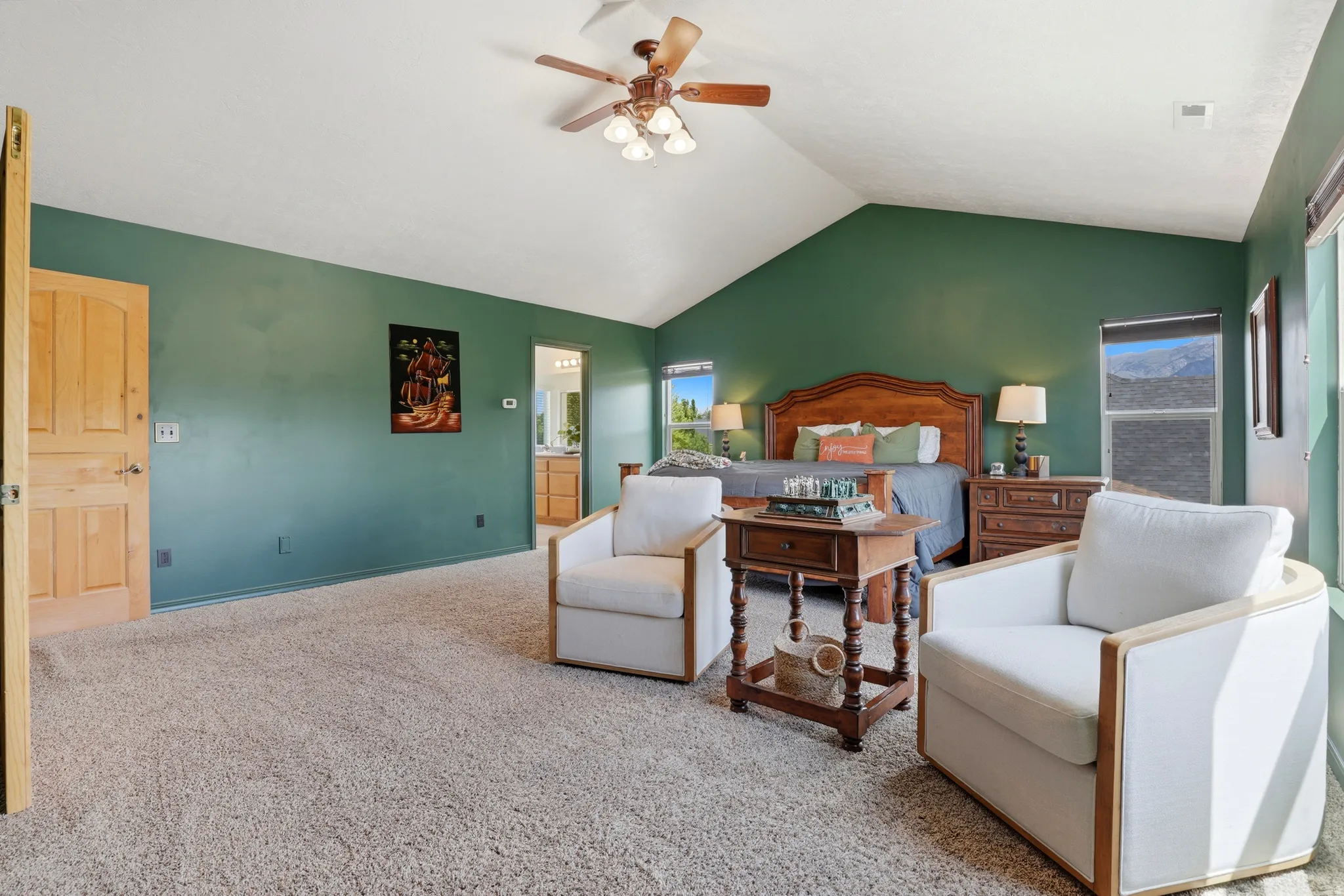 Spacious room featuring vaulted ceilings, a ceiling fan with integrated lighting, wood-finish interior doors, and plush carpeting