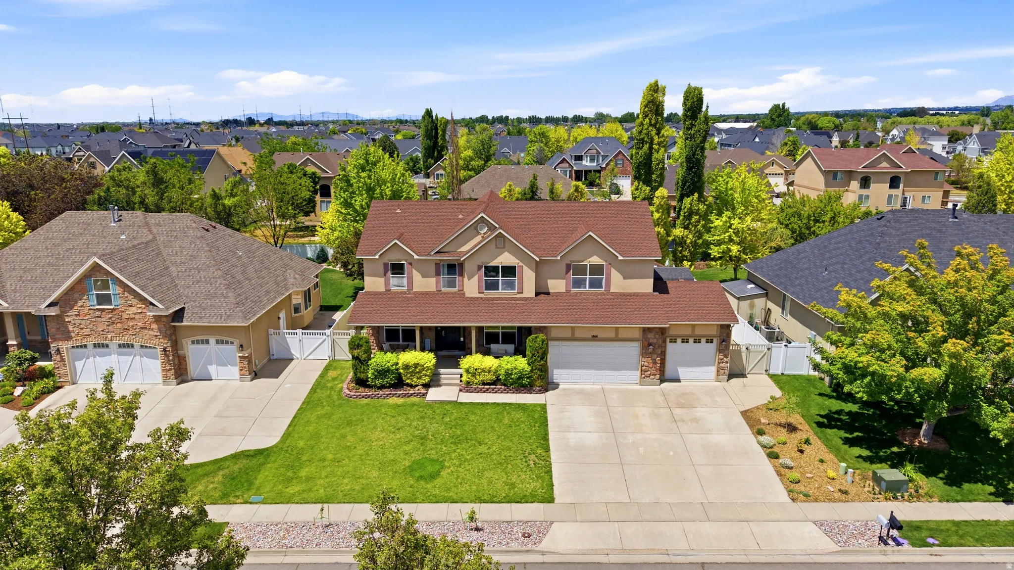 Two-story residence featuring a brown shingle roof and a combination of stucco and stone veneer siding