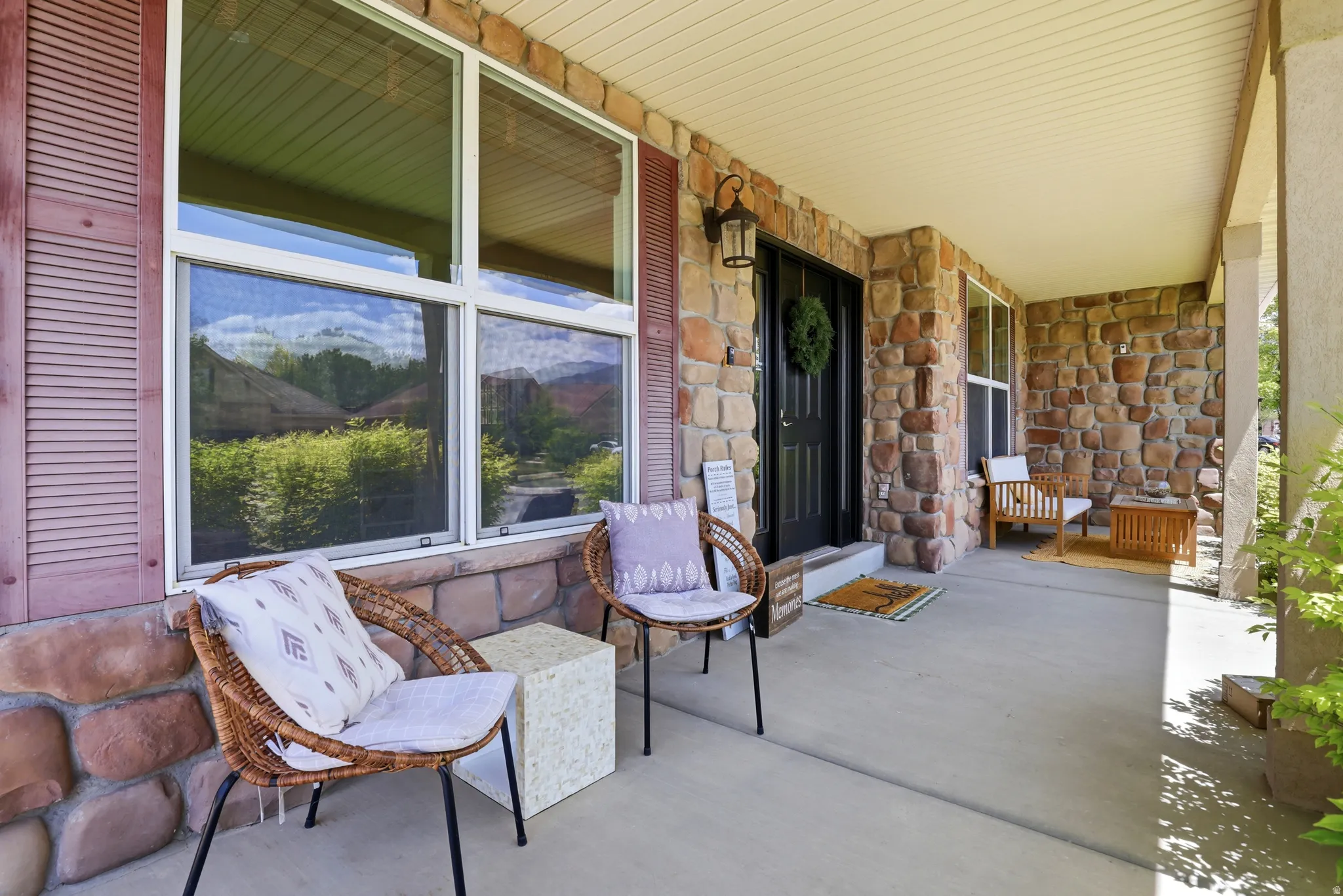 Inviting front porch featuring a stone facade, a covered entry, and a dark paneled door with an overhead lantern fixture