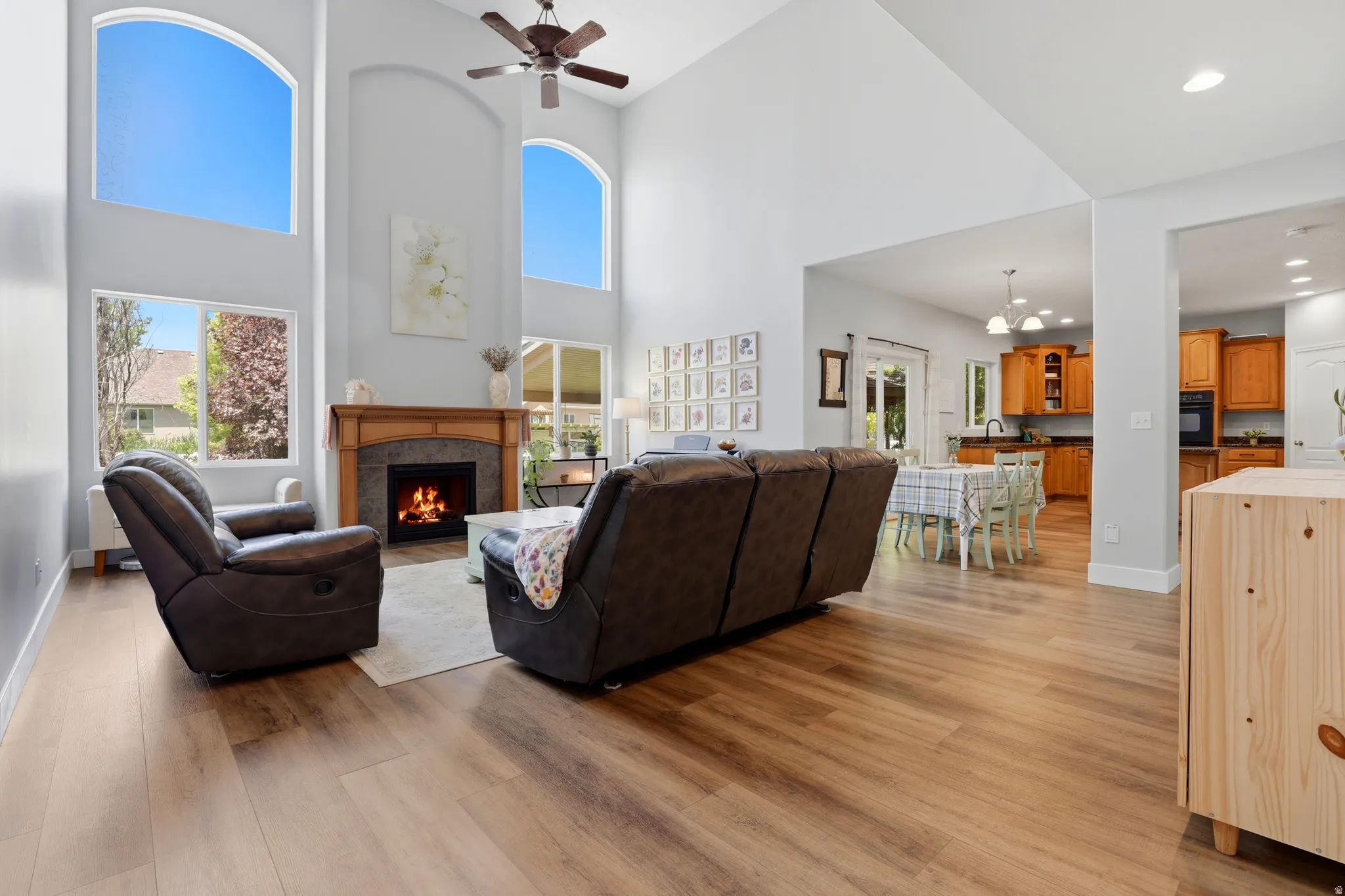 Vaulted ceiling living area with a stone-surround fireplace, wood mantel, and large arched windows