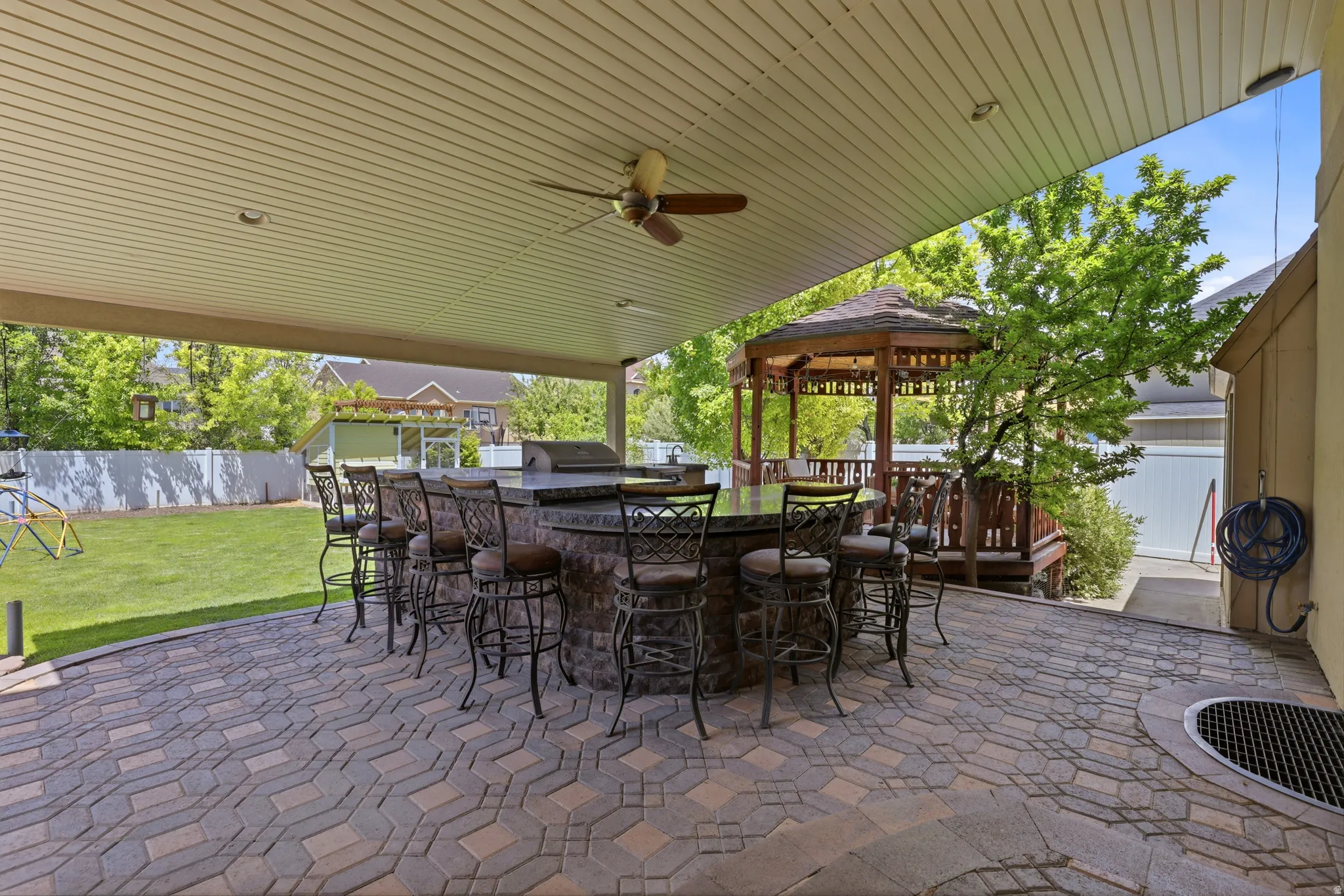 Covered patio featuring a large outdoor bar with stone-finish base, integrated countertop, and seating for multiple guests