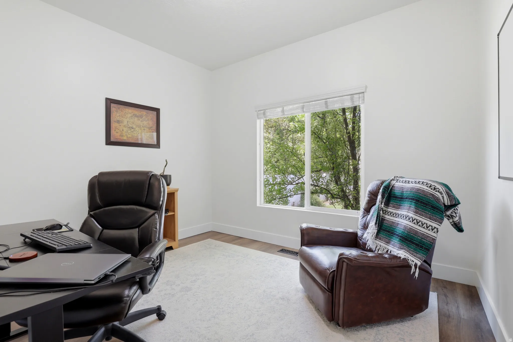 Bright room featuring a large window, neutral white walls, and wood-finish flooring